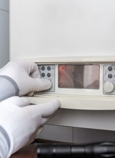 Technician servicing heating boiler in a house